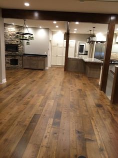 an empty kitchen and living room with wood flooring in the middle of the room