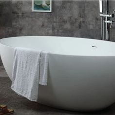 a white bath tub sitting on top of a bathroom floor next to a wall mounted shower head