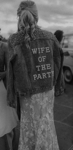 Bride wearing denim jacket embellished with pearls and back reading 'wife of the party' in the evening