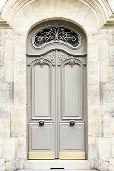 the front door to an old stone building with two large doors and wrought iron work