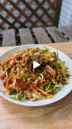 a white plate topped with salad on top of a wooden table