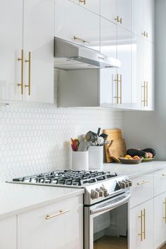 a stove top oven sitting inside of a kitchen next to white cupboards and drawers