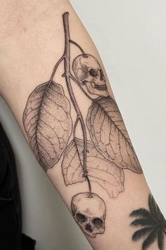 a skull and leaves tattoo on the arm