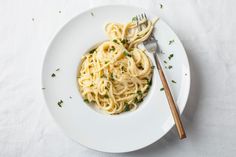 a white plate topped with pasta and garnished with parsley next to a fork