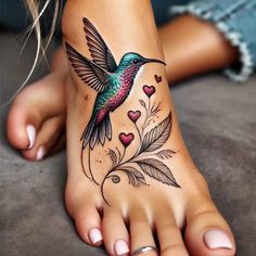 a woman's foot with a hummingbird and hearts tattoo on the bottom of it