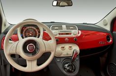 the interior of a small car with red and white trims, steering wheel, dash lights, and dashboard