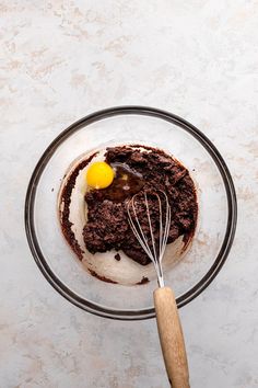 a glass bowl filled with chocolate cake and whisk