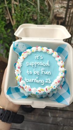 someone holding up a birthday cake with the words it's supposed to be fun turning 23