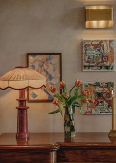 two vases with tulips on a table next to a lamp and pictures