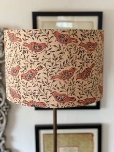 a lamp that is sitting on top of a table next to a wall with pictures