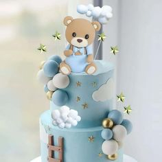 a teddy bear is sitting on top of a blue and white cake with gold stars