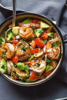 shrimp, avocado and tomato salad in a bowl with a fork on the side