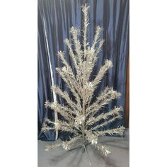 a silver christmas tree is on display in front of a blue curtain