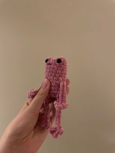 a hand holding a pink crocheted stuffed animal