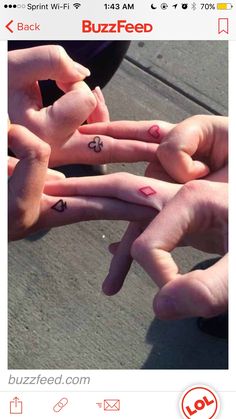 four people are holding their hands together with small tattoos on them