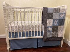 a white crib with a quilted blanket on the top and bottom rail, next to a wooden floor