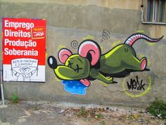 graffiti on the side of a building depicting a rat with its mouth open and tongue out