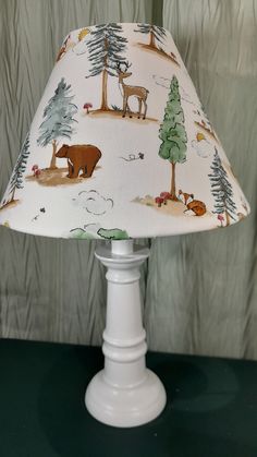 a lamp with a bear and deer print on the shade is sitting on a table