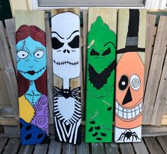 three painted skateboards sitting next to each other on a wooden bench with halloween decorations