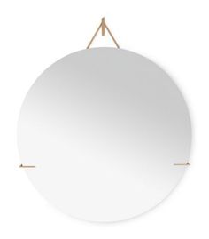 a white round mirror hanging on a rope with two gold pins in the middle and an empty