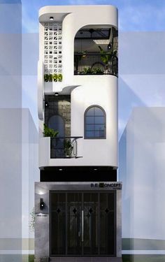 a tall white building with plants growing on it's side and windows above the entrance