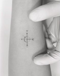 a woman's arm with a small compass tattoo on the left side of her body