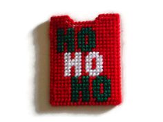 a cross stitch christmas ornament on a white surface with red and green trim