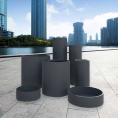 there are many round gray vases on the ground in front of a cityscape