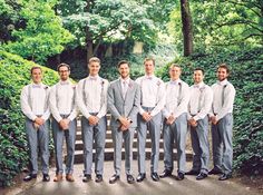 a group of young men standing next to each other in front of trees and bushes