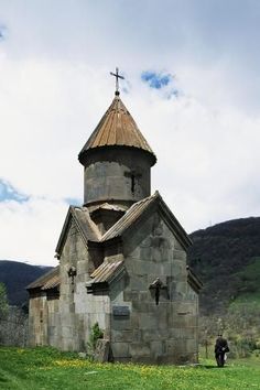 an old stone church with a cross on it's steeple in the mountains