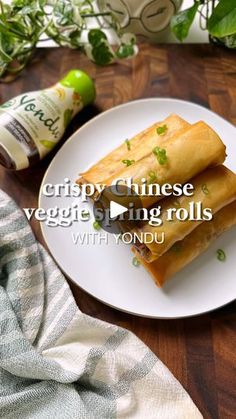 two vegetable spring rolls on a white plate with yogurt and herbs in the background