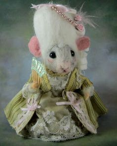 a stuffed animal mouse dressed in a dress and tiara with pearls on it's head