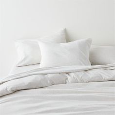 a bed with white sheets and pillows on it