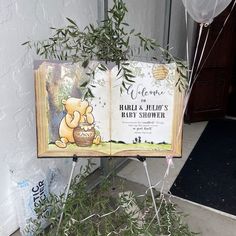 an open book sitting on top of a wooden stand next to a plant and balloons