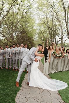 a bride and groom kissing in front of their wedding party