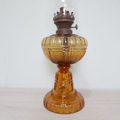 an old fashioned glass lamp with a crown on top is sitting on a white surface