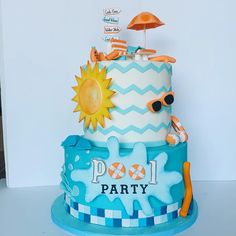 a blue and white cake decorated with an umbrella, sun and beach scene on top