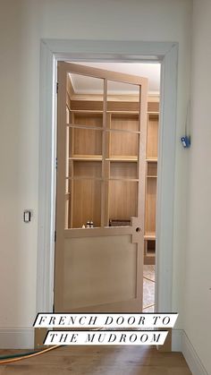 an open door leading into a room with shelves on the wall and wood flooring