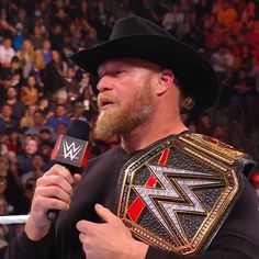 a man with a beard holding a microphone in front of an audience at a wrestling match