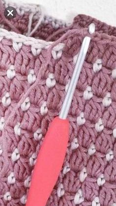 a crocheted blanket with a pink toothbrush sticking out of the end, on top of it