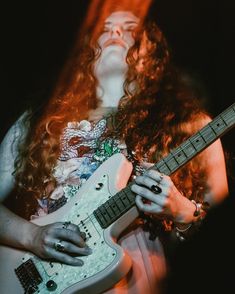 a woman with long hair playing an electric guitar