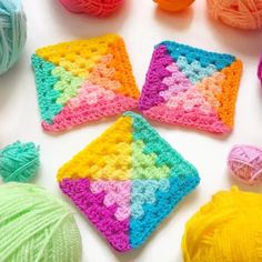 crocheted squares and balls of yarn are arranged on a white surface with multicolored colors