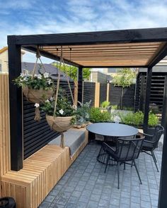 an outdoor dining area with wooden benches and plants in hanging baskets on the side wall