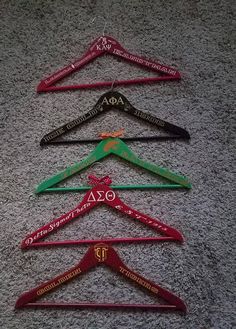 five different colored clothes hangers with names on them sitting on the floor next to each other