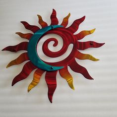 a red and yellow metal sun decoration on a white wall