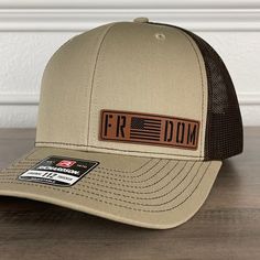 Freedom American Flag Patriotic Leather Patch Hat Khaki/Brown. Specifications: 🧢 Richardson original 112 trucker; adjustable for the perfect fit 🎩 60/40 cotton/polyester blend for comfort 📏 One size fits most 🏷️ Expertly laser engraved leatherette patch design 📦 Ships in 2 to 3 business days from our Orlando Studio Care Instructions: 🚫 Do not wash; spot clean only Please Note: 🌈 Colors may vary from photos based on your viewing screen. Brown Flat Bill Baseball Cap For Outdoor, Brown Adjustable Cap, Brown Outdoor Baseball Cap, Adjustable Brown Cap, Brown Casual Trucker Hat With Curved Brim, Casual Brown Trucker Hat With Curved Brim, Brown Adjustable Baseball Cap For Fall, Brown Flat Bill Snapback Hat For Outdoor, Brown Adjustable Hat With Curved Bill