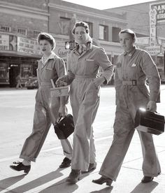 three women in overalls are walking down the street