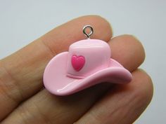 a tiny pink toy hat with a heart on it's center, sitting in someones hand