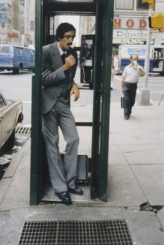 a man in a suit is standing on a phone booth