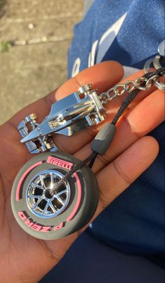 a person holding a keychain that has a wheel and chain attached to it